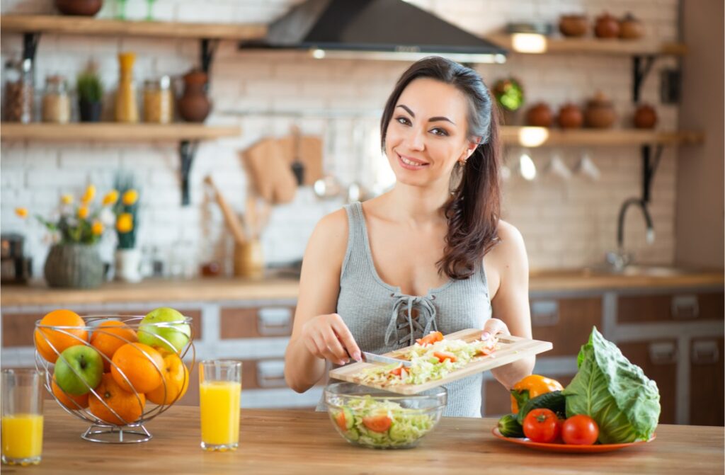 pretty young woman cutting vegetables