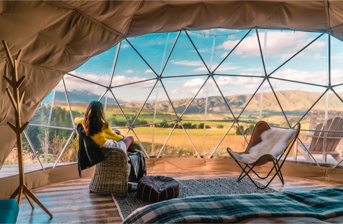 woman looking out at nature from geo dome tents