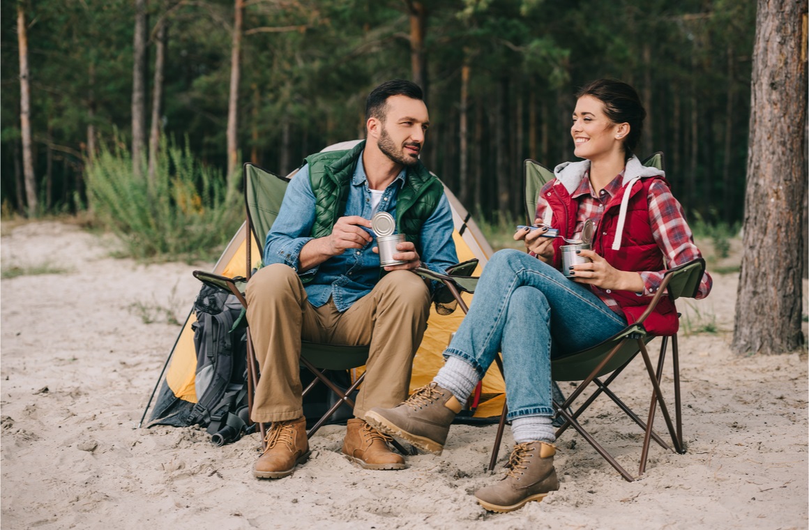 couple eating food from cans while having camping