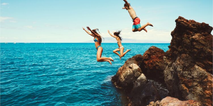 Friends jumping into the ocean