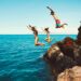 Friends jumping into the ocean