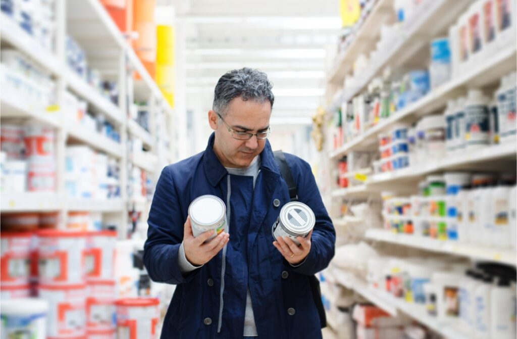 man choosing paints on hypermarket