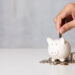 man hand putting coins on pig