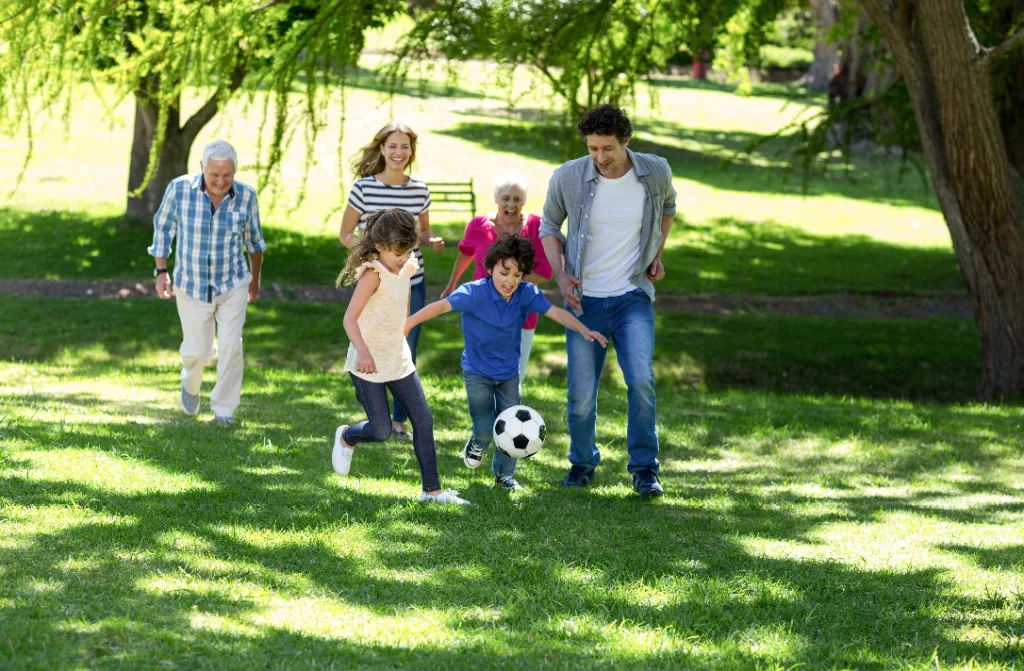 smiling family playing fotball garden