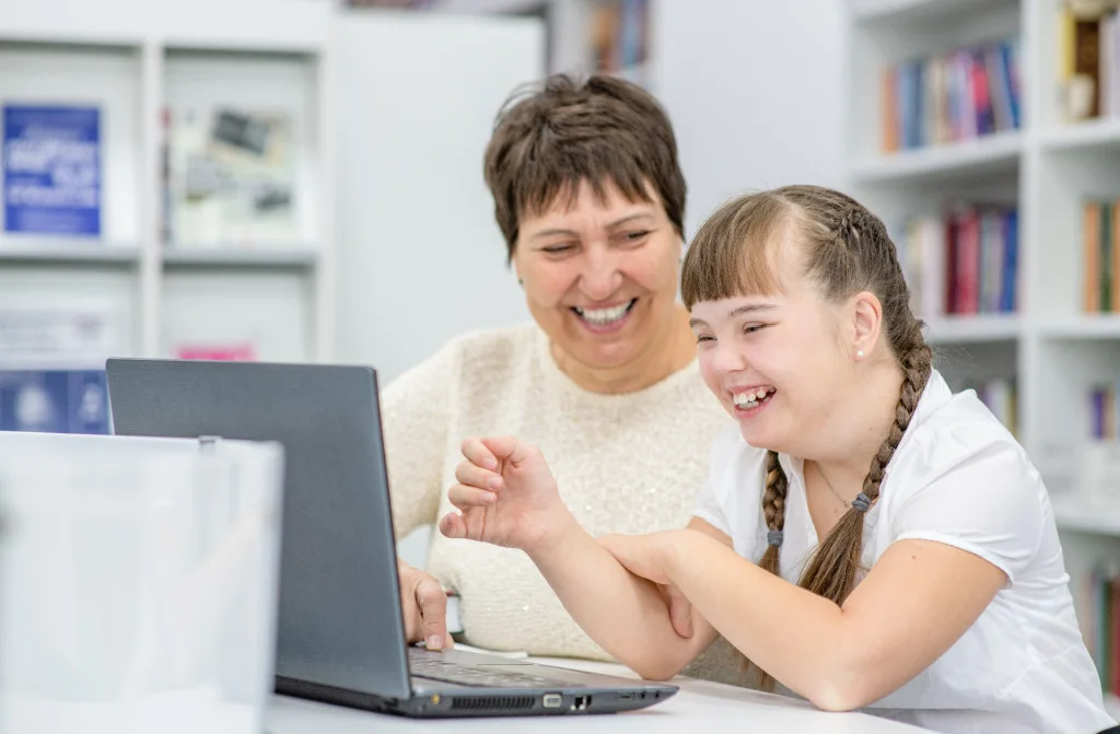smiling girl syndrom down using laptop