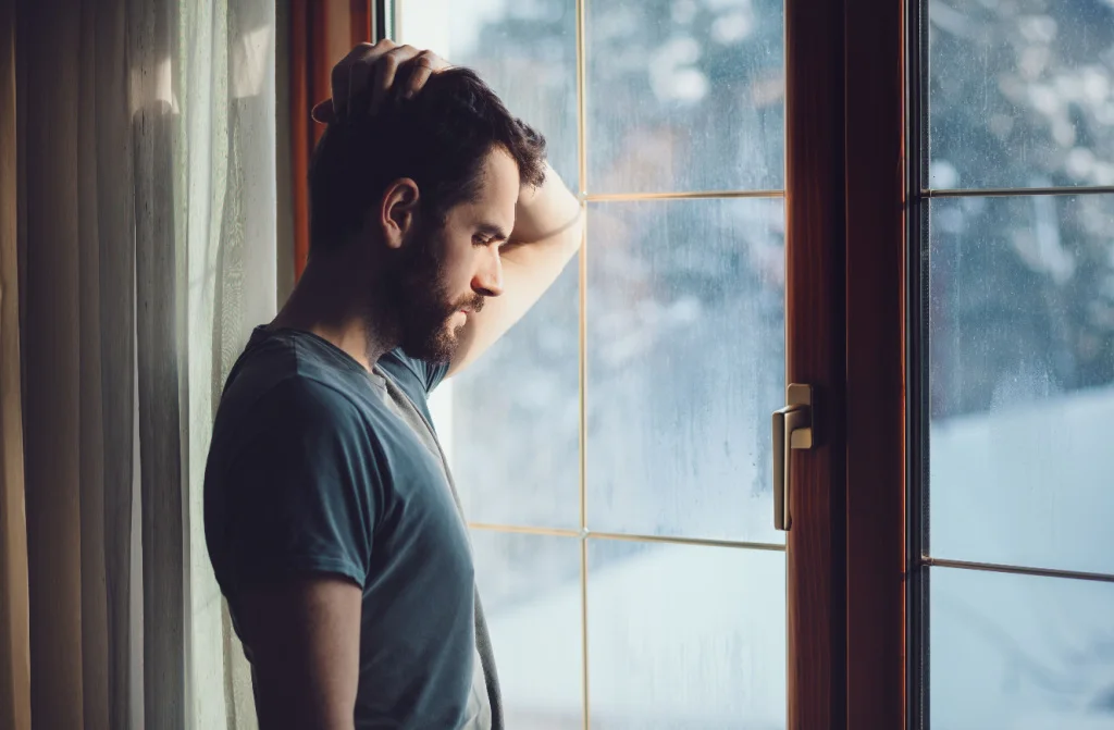 sad young man sitting by window